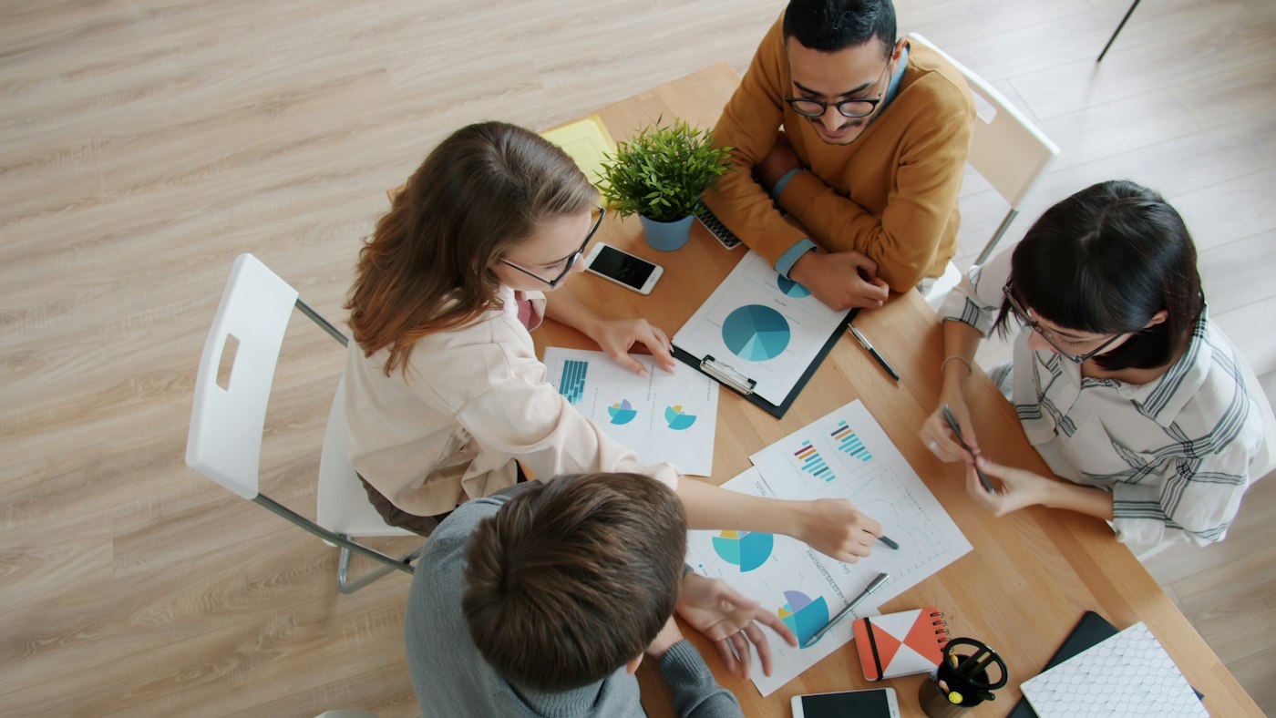A group reviewing charts around a wooden table, a stock photograph