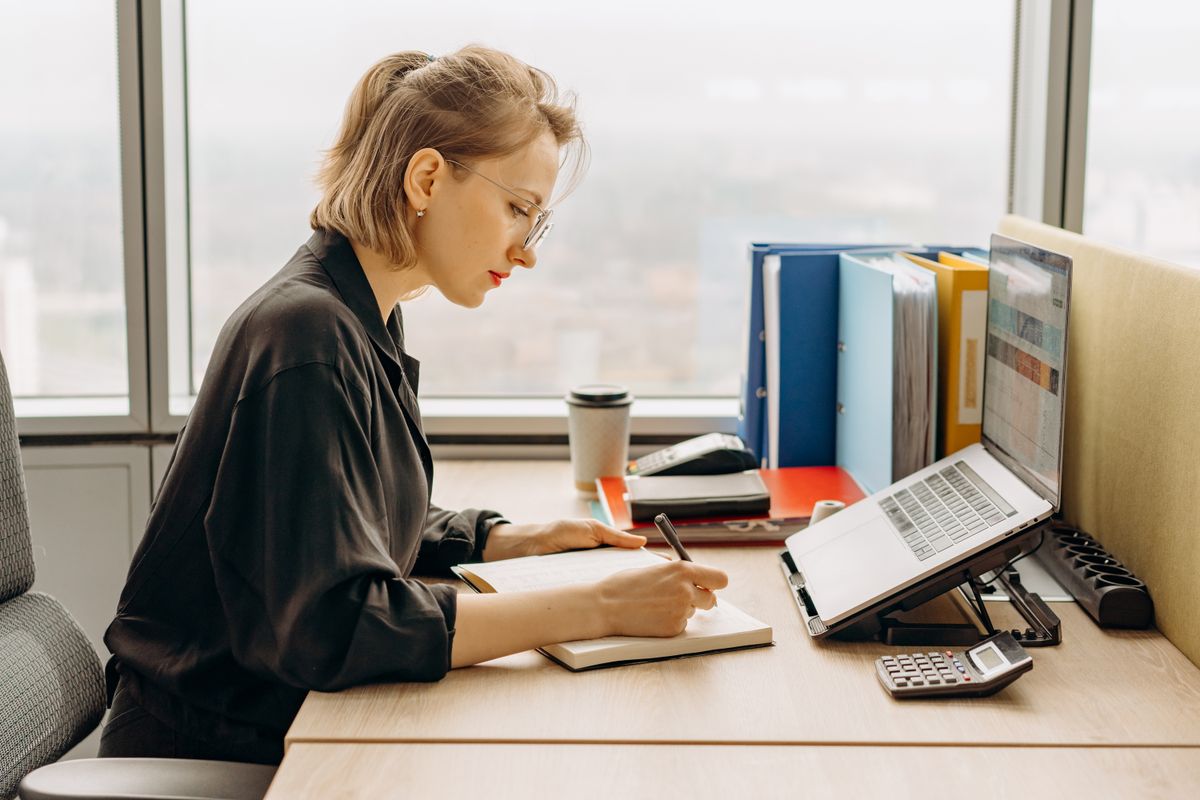 A person writing notes beside a laptop, a stock photograph